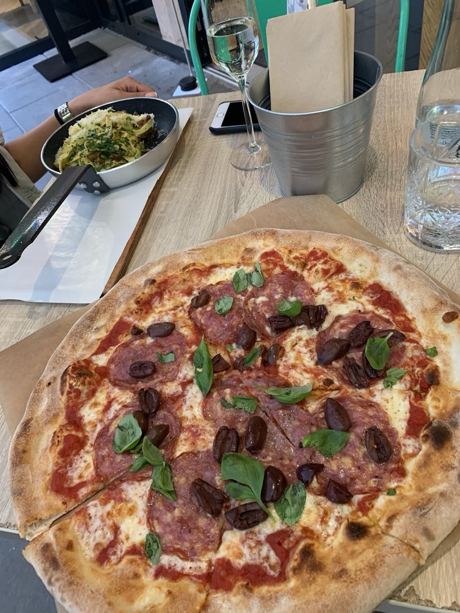 Pizza z cienkim, przypieczonym brzegiem i kolorowymi dodatkami.